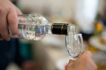 the waiter pours an alcoholic drink, vodka into a glass.