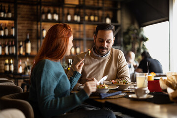 Valentines day couple sitting in favourite caffe, exchanging gifts in hart shape, couple cudling and hugging