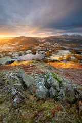 Fototapeta na wymiar Lake District Sunrise on a Winter morning at Loughrigg Fell with rocks in foreground. British landscape photography.