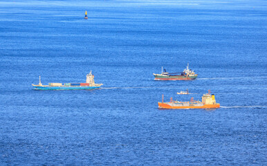 Small Fleet of Cargo Ships Sail through Shipping Lane in Calm Blue Sea