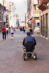 Hombre en silla de ruedas circulando por calle de ciudad.