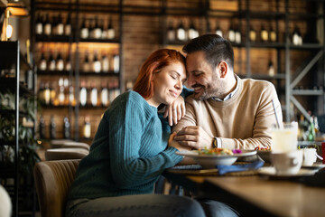 Valentines day couple sitting in favourite caffe, exchanging gifts in hart shape, couple cudling and hugging