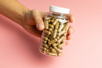 Hand holding a jar with ashwagandha capsules, immunity support, health care, body supplementation