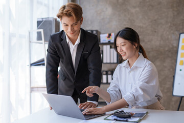 Obraz premium Two Asian business people are consulting on marketing planning, a new corporate sales strategy in line with current events.