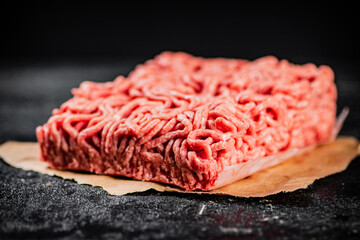 Raw minced meat on paper on the table. 