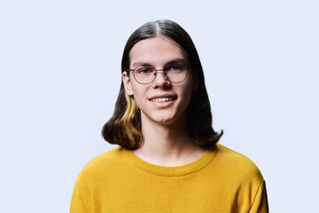 Headshot portrait of smiling teenage guy on light studio background