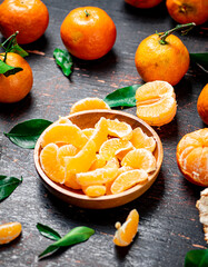 Pieces of fresh tangerines on a plate with leaves. 