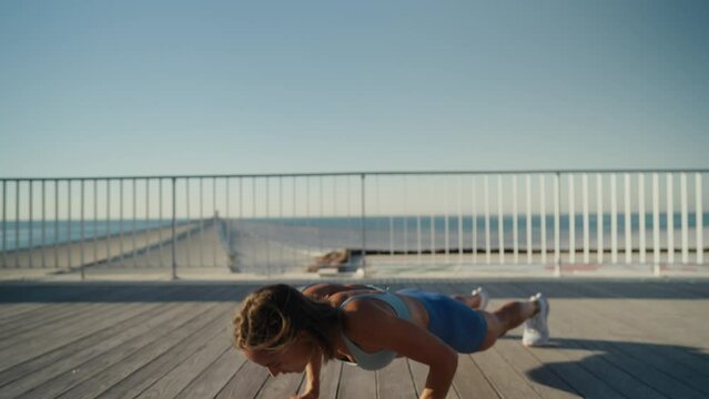 Sportswoman workout outdoor on seaside - she make burpee exercise. High quality 4k footage