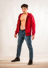 Athletic young man undressing, with open red hoodie