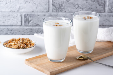 Kefir, buttermilk or yogurt with granola. Yogurt in glass on white wooden background