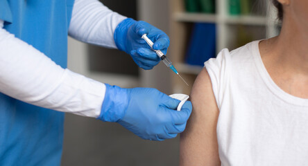 Hands of doctor in protective gloves make injection with syringe of old caucasian female patient in...