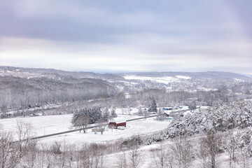 Obraz premium Peaceful winter scene with a red barn in the middle of a snowy hilly field. Upstate New York