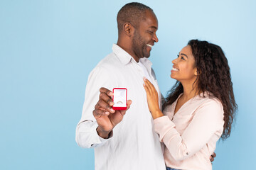 Affectionate black couple hugging and looking at each other, middle aged man holding box with...