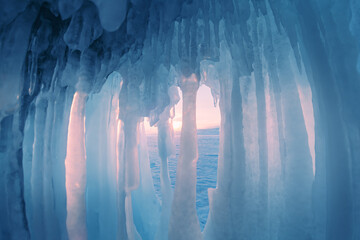Ice cave with icicles on Baikal lake at sunset