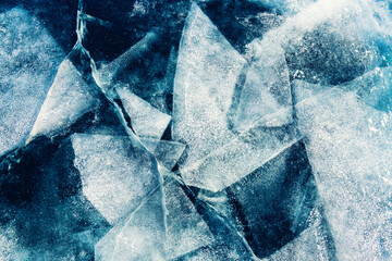 Transparent blue ice with cracks and ice floes on Baikal lake in winter.