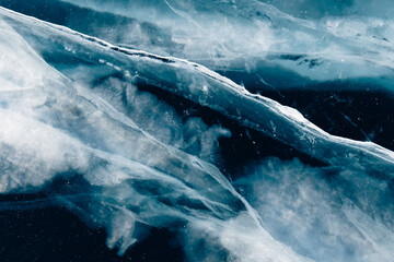 Transparent blue ice with cracks on Baikal lake in winter.