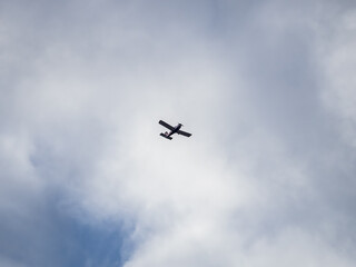 Small ultralight airplane with overhead wing and single propeller flying in sunset sky.