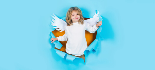 Child angel in paper hole. Portrait of angelic kid. Little cupid boy in white wings. Christmas kids.