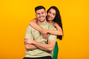 Happy young middle eastern lady in green dress hugging boyfriend, celebrate party event