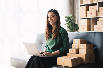 Start up small business, SME female owner checking order online to prepare to pack a box of goods for sale to customers, sme business idea.