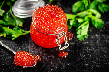 Red caviar in a glass jar with parsley. 