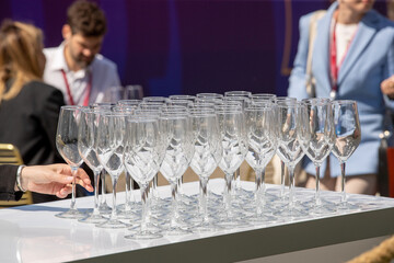 A woman - a waiter serves glasses and serves a table in the open air. Glasses for wine and champagne on a buffet table