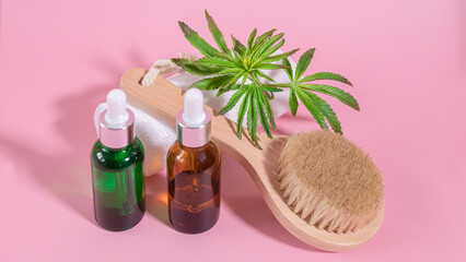 Black and green glass non-branded cosmetic oil and cannabis essential oil bottles and natural bristle wooden facial cleansing brush. Natural skin care and aromatherapy.Spa, wellness, massage concept