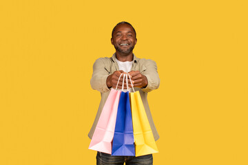 Cheerful african american middle aged man shopaholic show many packages with purchases from shop