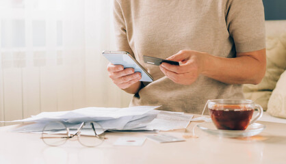 Woman holds phone in her hands for paying bills, receipts of financial checks, budget planning