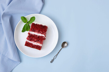 A piece of red velvet sponge cake white plate, pastel blue background. Festive dessert - obrazy, fototapety, plakaty