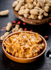 Peanut butter and inshell peanuts in wooden plates. 