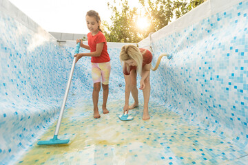 mother and daughter cleaning swimming pool in the garden.
