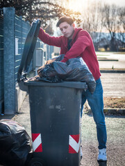 Attractive young man putting out rubbish standing