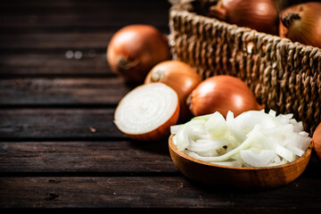 Pieces of onion in a plate and whole onions in a box. 