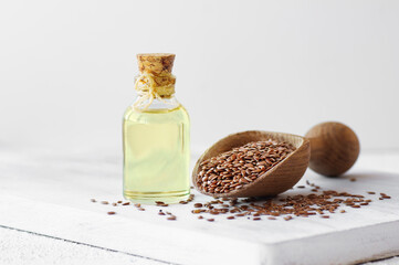 Glass bottle of linseed or flaxseed oil with flax seeds on rustic table, oil dietary fiber...