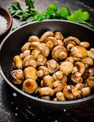 Frying pan with fried small mushrooms with parsley. 