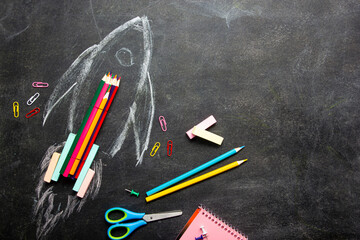 Back to school concept. School supplies on black board background.