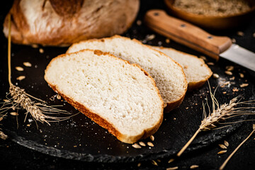 Sliced on a stone board wheat bread with grains. 