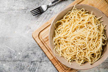 Full bowl with boiled spaghetti on a cutting board. 