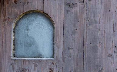 Wooden wall with small window in frost. Cold morning.