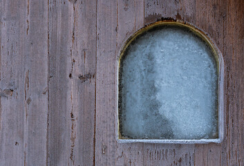 Wooden wall with small window in frost. Frost on the window