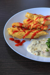 Plate of grilled chicken with mushroom sauce on wooden background.
