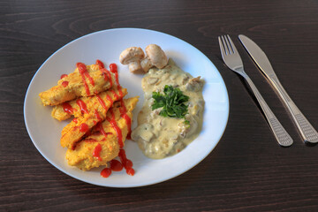 Plate of grilled chicken with mushroom sauce on wooden background.