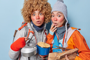 Photo of two frightened women stare impressed reacts to something breathtaking have picnic together...