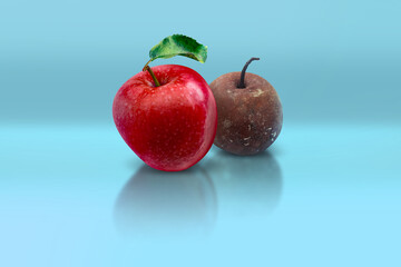 Ripe fresh red apple and bad rotten spoiled apple behind on blue background.