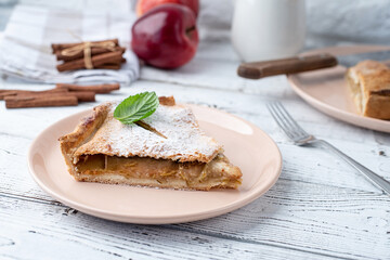 Homemade piece of apple pie with fresh red apples on white table