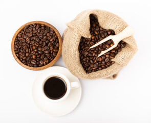 A cup of aromatic coffee and coffee beans in a bowl and burlap isolated on a white background.
