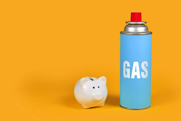 Gas cartridge bottle with piggy bank on yellow background. Concept for saving gas