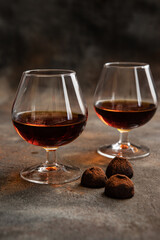 Glass of brandy  or cognac and  chocolate truffles on dark table
