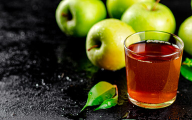 A glass of green apple juice with leaves on the table. 